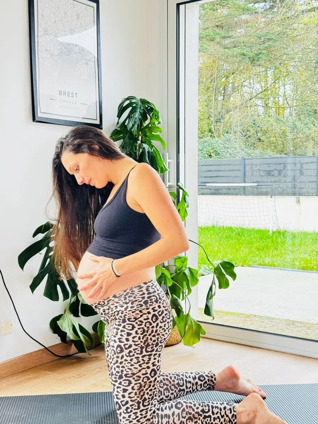 Nolwenn enceinte à genoux sur son tapis, mains sur le ventre
