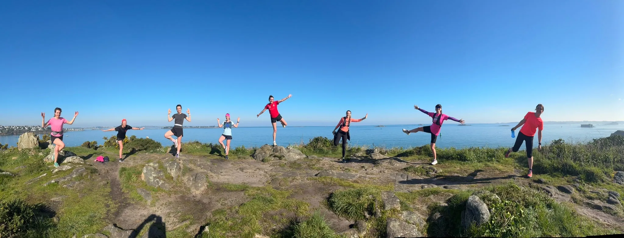 Groupe de coureuses en poses sportives sur un sentier côtier, vue panoramique